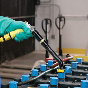 A man using a Philadelphia Scientific Battery Watering Gun to water a lead acid battery